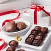 Two tier white box perfect gift set filled with turtles, caramels and assorted chocolates and tied with a red satin bow.