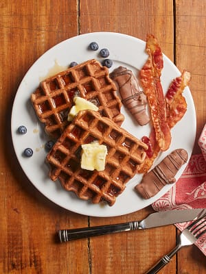 chocolate covered bacon and waffles on plate