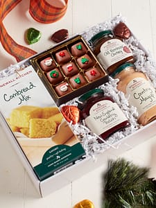 White box filled with a holiday feast of chocolate caramels, cornbread and gourmet jams and sauce.