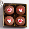 4 valentine's chocolate sandwich cookies with heart icing decals in a box