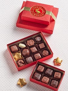 two red boxes of assorted chocolates, creams and caramels tied with a gold bow with sweet layers