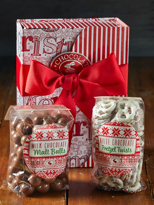 Holiday Classics Chocolate Gift Box with a bag of malt balls and white chocolate pretzels.